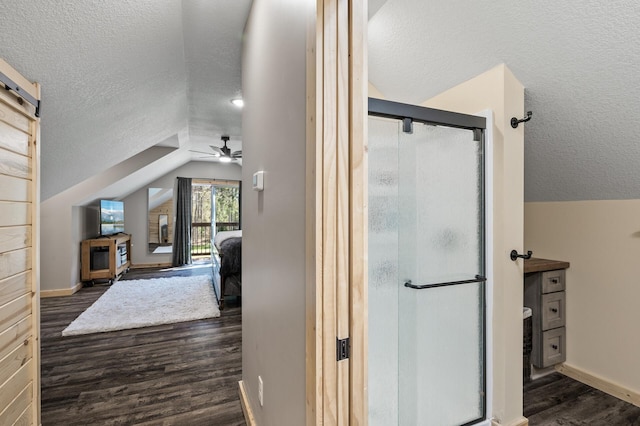 bathroom with a textured ceiling, ceiling fan, a shower stall, vaulted ceiling, and wood finished floors