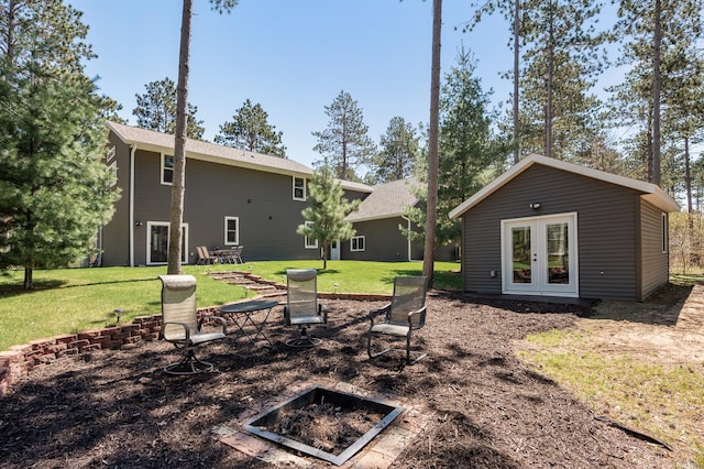 rear view of property with a lawn, an outbuilding, and french doors