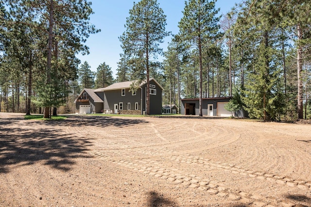 view of front of home with dirt driveway and a garage