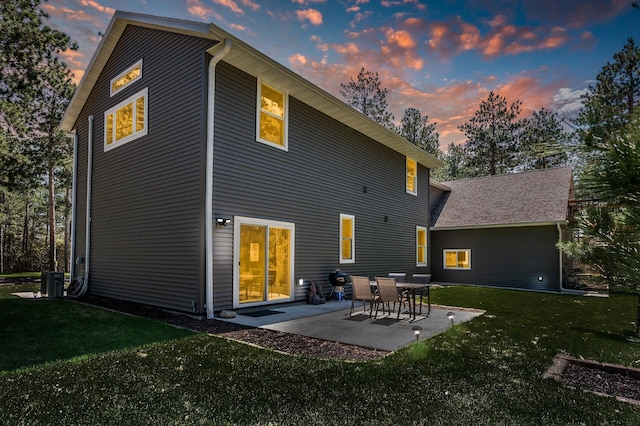 back of house at dusk featuring a yard, a patio area, and cooling unit