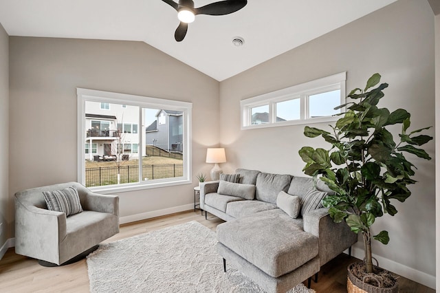 living area with baseboards, ceiling fan, light wood finished floors, and lofted ceiling