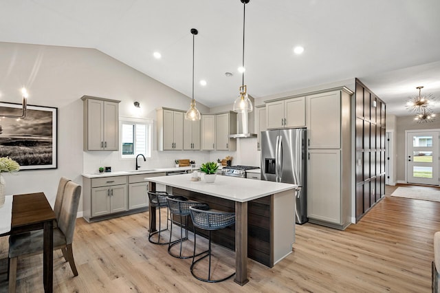 kitchen with a breakfast bar area, light countertops, vaulted ceiling, gray cabinetry, and stainless steel appliances