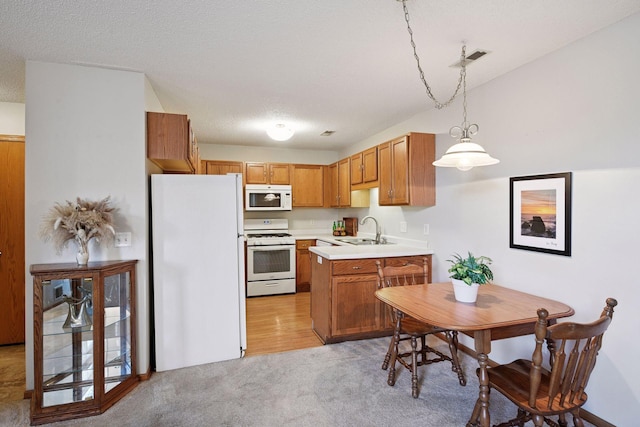 kitchen with light colored carpet, pendant lighting, a sink, light countertops, and white appliances