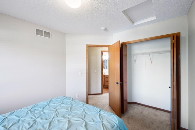 bedroom featuring visible vents, a closet, attic access, a textured ceiling, and carpet flooring