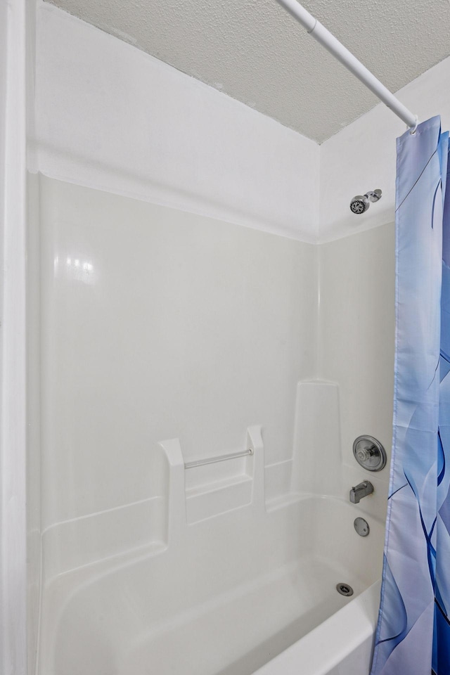 full bathroom with shower / bath combo and a textured ceiling