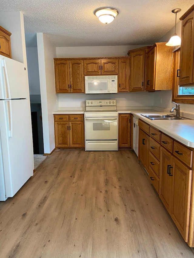 204 8th St N, Sartell, MN 56377 - kitchen with white appliances, brown cabinetry, light wood-type flooring, a sink, and a textured ceiling