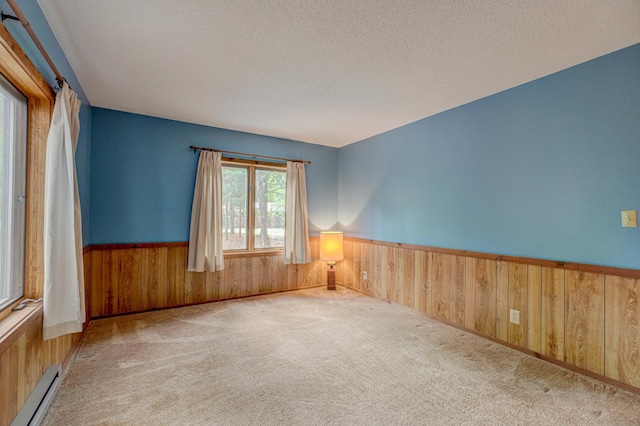 10121 Comstock Rd, Hayward, WI 54843 - carpeted spare room with a baseboard heating unit, wood walls, a wainscoted wall, and a textured ceiling