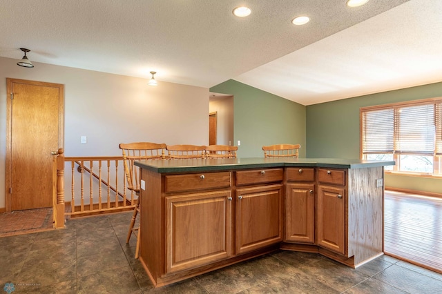 23898 324th Ave, Sverdrup Twp, MN 56586 - kitchen with a kitchen bar, a textured ceiling, a kitchen island, and dark countertops