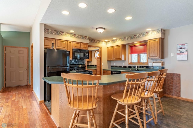 23898 324th Ave, Sverdrup Twp, MN 56586 - kitchen with baseboards, a breakfast bar, black appliances, and a sink