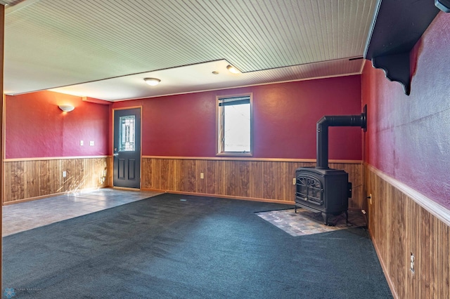 23898 324th Ave, Sverdrup Twp, MN 56586 - unfurnished living room featuring a wood stove, wood walls, carpet floors, and a wainscoted wall