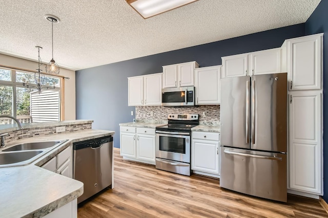 kitchen featuring appliances with stainless steel finishes, tasteful backsplash, a textured ceiling, light countertops, and a sink