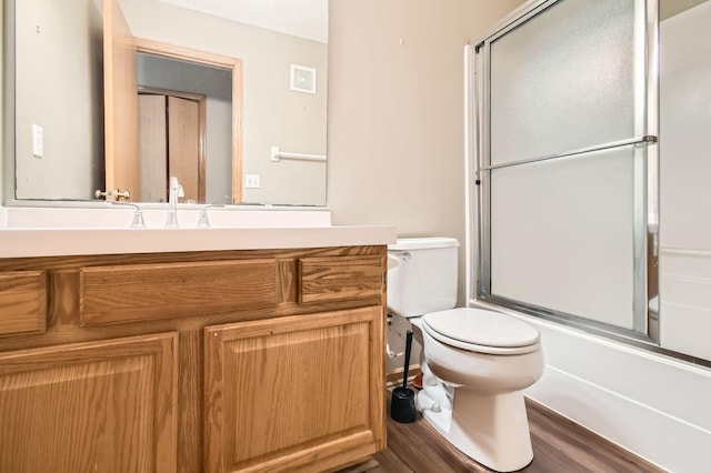 full bathroom featuring toilet, vanity, bath / shower combo with glass door, and wood finished floors
