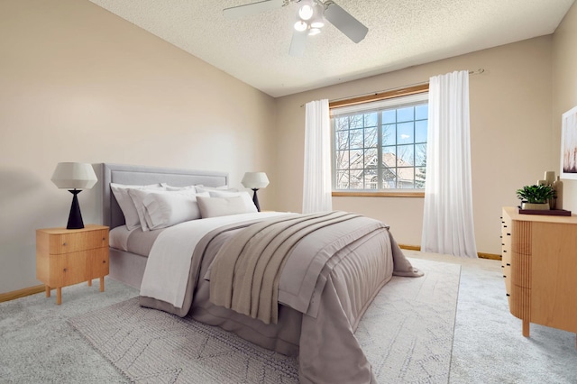 carpeted bedroom featuring a textured ceiling, baseboards, and ceiling fan