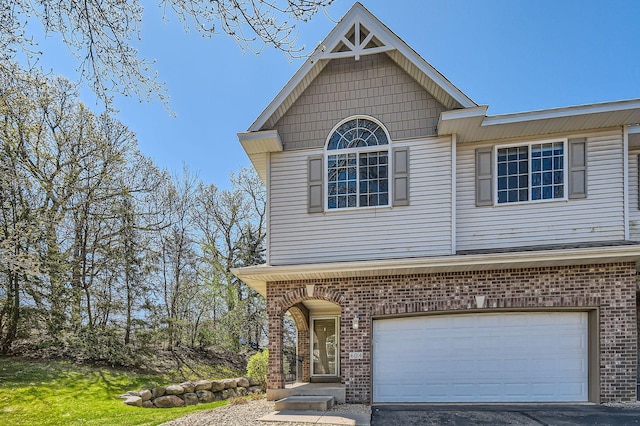 view of front facade with brick siding, a garage, and driveway