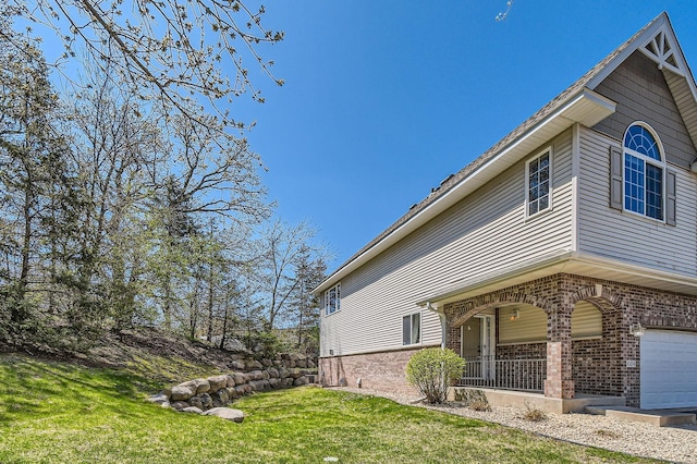 view of property exterior featuring brick siding, a yard, and an attached garage