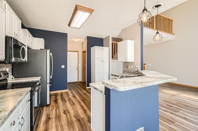 kitchen with stainless steel appliances, a sink, wood finished floors, baseboards, and white cabinetry