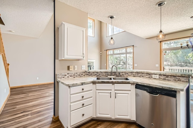 kitchen with dishwasher, a textured ceiling, a sink, a peninsula, and wood finished floors
