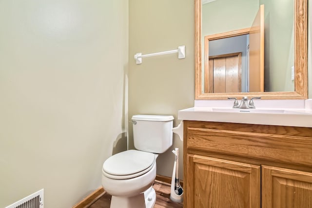 bathroom featuring toilet, vanity, wood finished floors, and baseboards