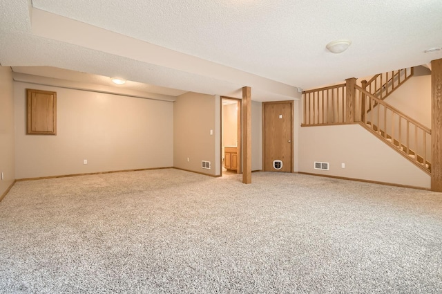 finished basement featuring carpet floors, a textured ceiling, baseboards, and stairs