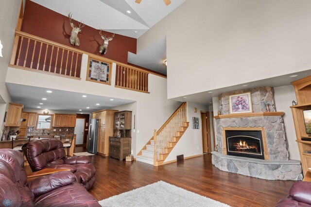 6435 172nd Ave SE, Colfax, ND 58018 - living room featuring ceiling fan, dark wood-style flooring, a towering ceiling, a fireplace, and stairs