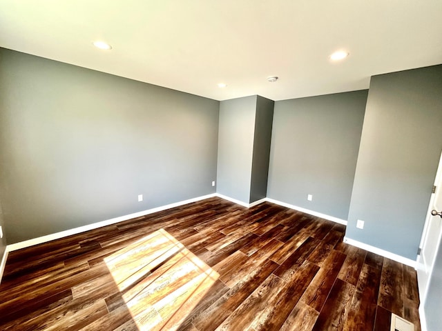 spare room featuring baseboards, visible vents, and dark wood finished floors