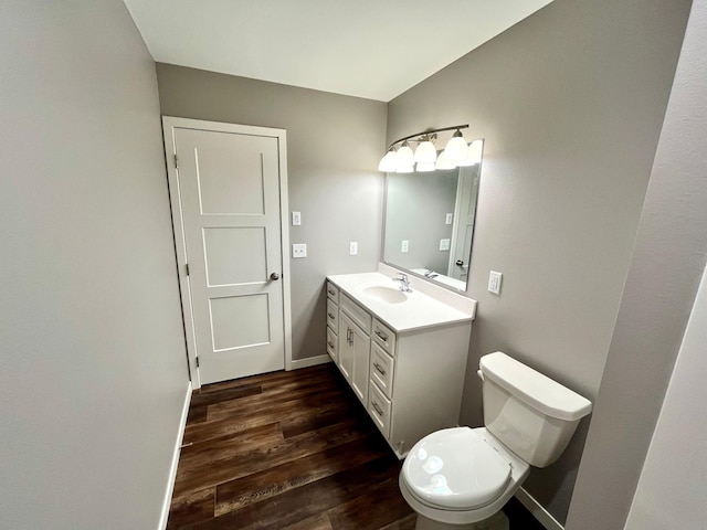 half bathroom with toilet, baseboards, wood finished floors, and vanity