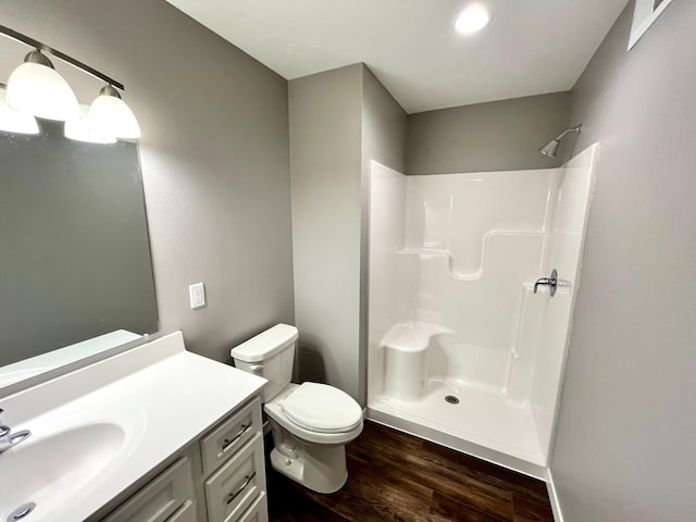 bathroom with walk in shower, vanity, toilet, and wood finished floors