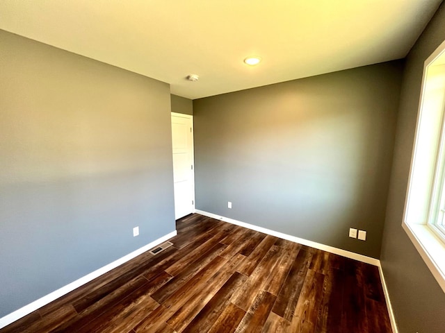 unfurnished room with dark wood-type flooring, baseboards, visible vents, and recessed lighting