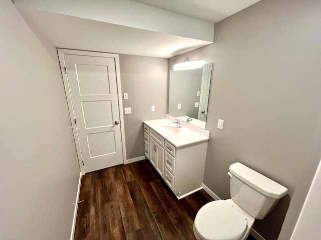 bathroom with toilet, baseboards, wood finished floors, and vanity