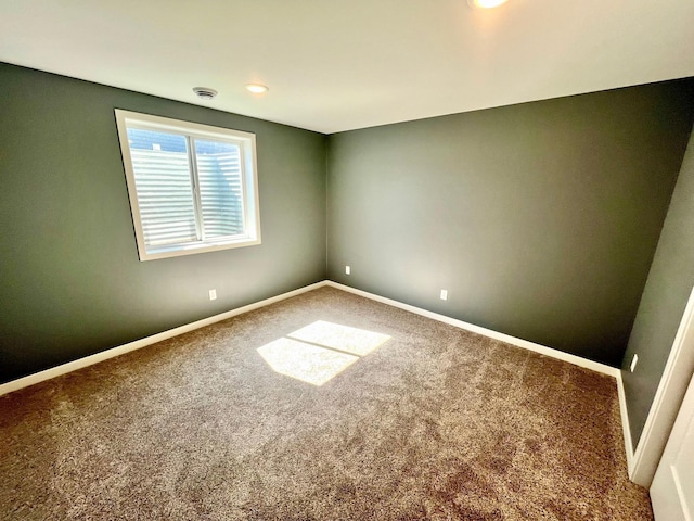 carpeted empty room featuring baseboards