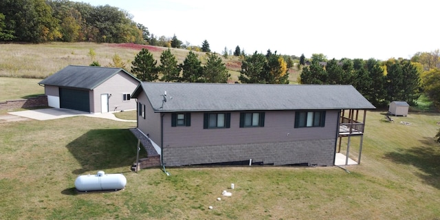 view of side of home with a yard, an outdoor structure, and concrete driveway