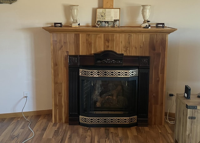 interior details with baseboards, a tiled fireplace, and wood finished floors