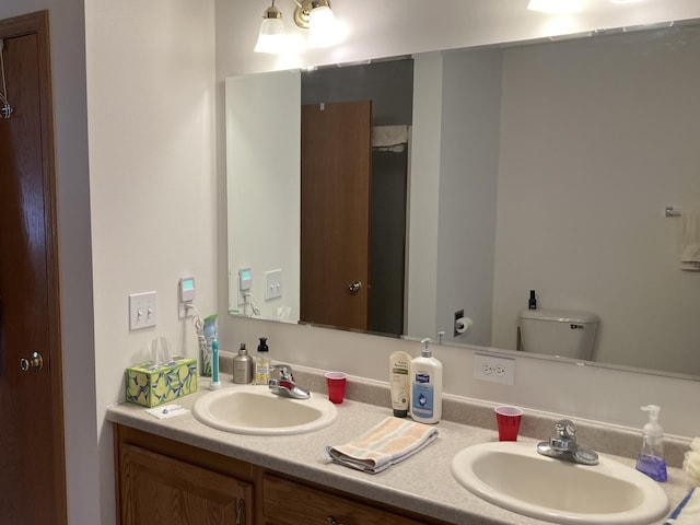 bathroom with double vanity, toilet, and a sink