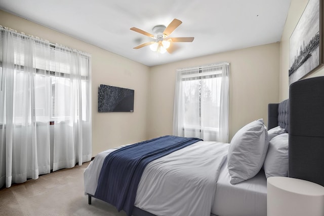 bedroom with light colored carpet and a ceiling fan
