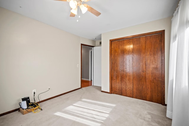 unfurnished bedroom featuring carpet flooring, a closet, baseboards, and a ceiling fan
