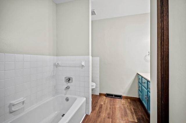 bathroom featuring a bath, wood finished floors, vanity, and toilet