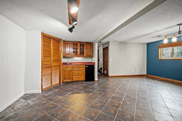 kitchen with a textured ceiling, brown cabinets, and baseboards
