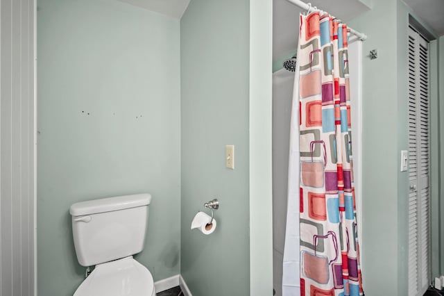 full bath featuring toilet, a shower with shower curtain, and baseboards
