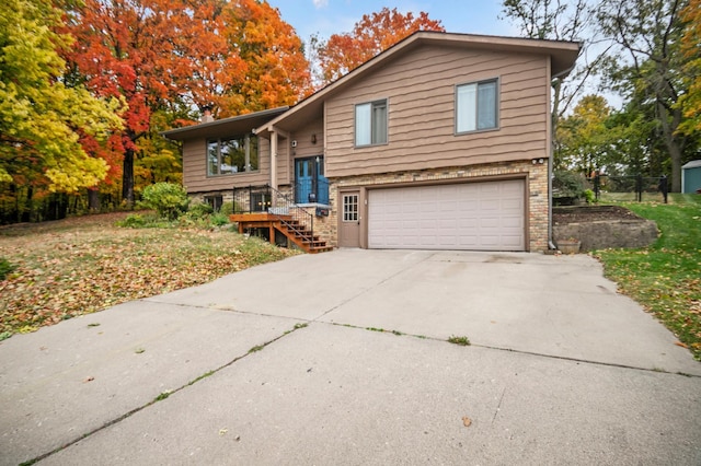 raised ranch with concrete driveway, brick siding, and an attached garage
