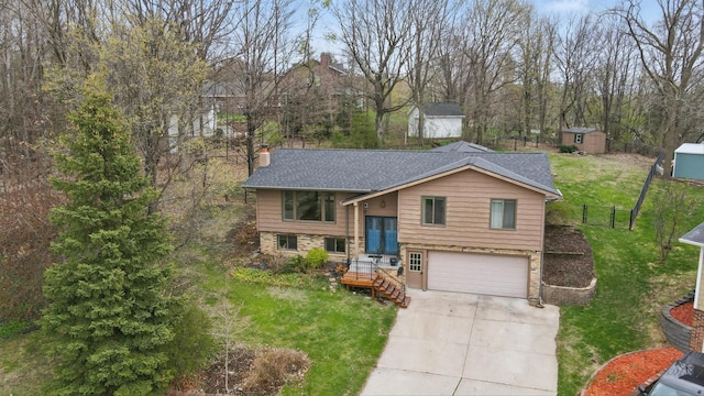bi-level home featuring a storage unit, concrete driveway, a garage, a chimney, and an outbuilding