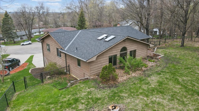 view of side of home featuring a shingled roof and a gate