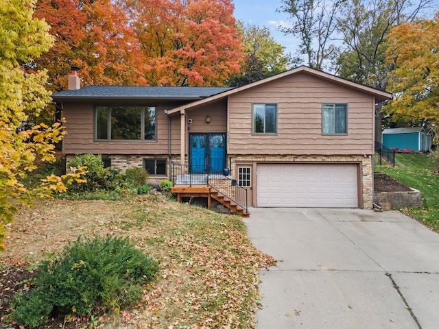 raised ranch with a garage, a chimney, and driveway
