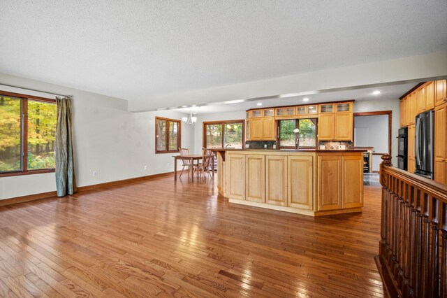 kitchen featuring stainless steel fridge, hardwood / wood-style floors, a chandelier, baseboards, and glass insert cabinets