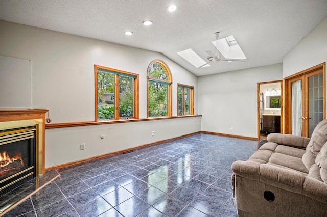 living area with a skylight, lofted ceiling, a glass covered fireplace, baseboards, and recessed lighting