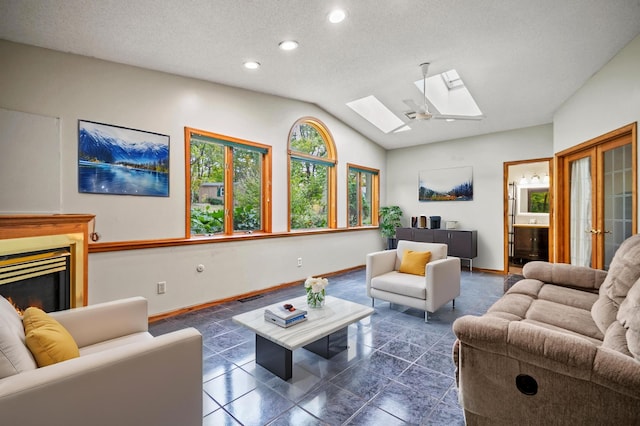 living area with a skylight, baseboards, vaulted ceiling, recessed lighting, and a glass covered fireplace