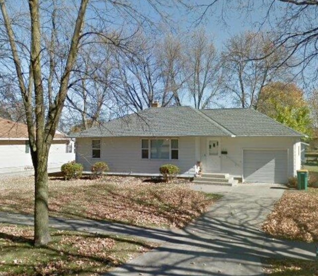 ranch-style home with a garage, driveway, and a chimney