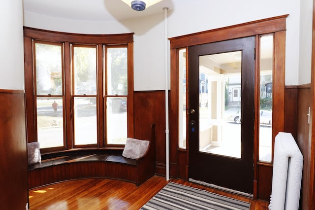 238 Lincoln St, Mankato, MN 56001 - doorway to outside featuring wood finished floors, wainscoting, and radiator heating unit