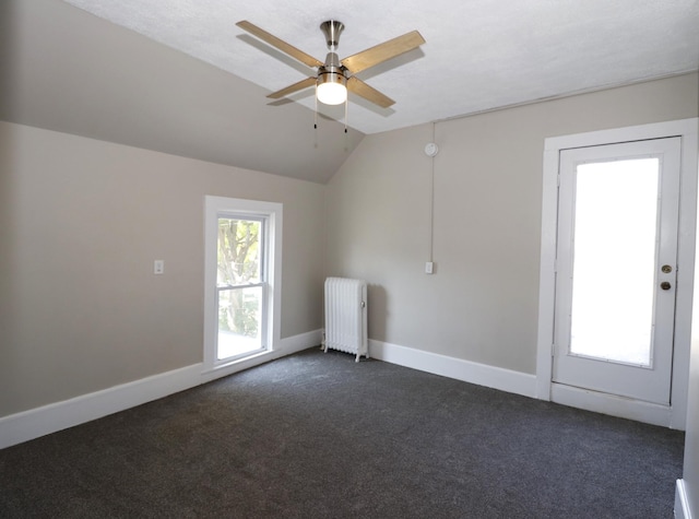 238 Lincoln St, Mankato, MN 56001 - empty room featuring ceiling fan, radiator heating unit, dark colored carpet, baseboards, and vaulted ceiling