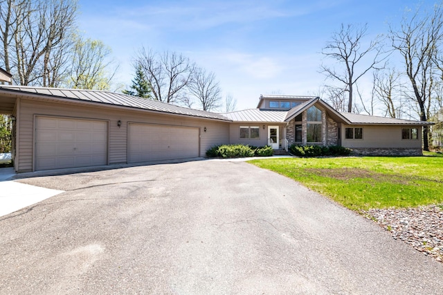 mid-century inspired home featuring asphalt driveway, an attached garage, a front lawn, metal roof, and stone siding