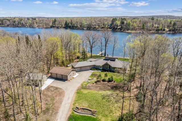 aerial view of property and surrounding area featuring a nearby body of water and a forest